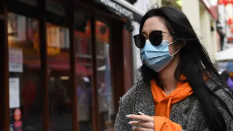EPA A woman wears a face mask in Chinatown in London, Britain, 04 February 2020. London"s Chinatown is feeling the impact of the Coronavirus as restaurants are seeing a down in customers following the confirmation of new coronavirus cases in the UK.