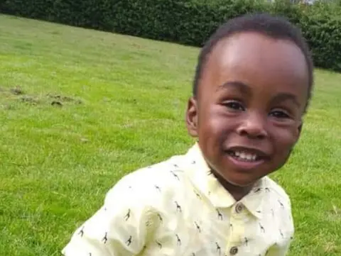 PA Media Two-year-old Awaab Ishak seen smiling into the camera while playing on an area of grass