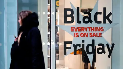 Getty Images Shoppers pass a promotional sign for 'Black Friday' sales discounts, outside a store on Oxford Street in London, on November 26, 2019