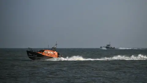 Getty Images Dungeness Lifeboat at sea with a Border Force vessel behind it