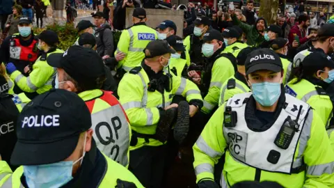 Getty Images Police officers arrest an anti-lockdown protester in Bristol