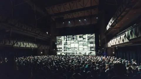 Here & Now Creative Simple Things Festival showing a packed main hall at the Bristol Beacon with the stage illuminated