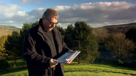 Sammy Wilson reading newspaper