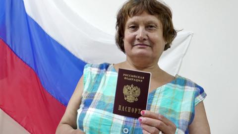 A woman holds her new Russian passport in Kherson, 2022
