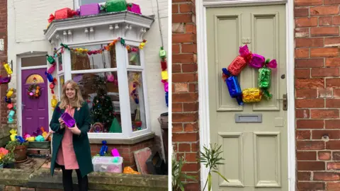 BBC Kayleigh Thomas stands outside her home which is decorated with oversized Quality Street replicas