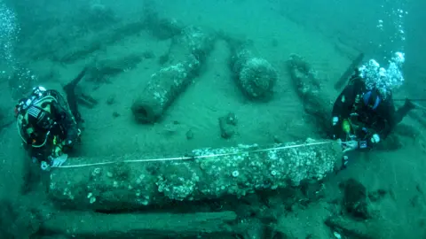 Norfolk Historic Shipwrecks / PA The brothers measuring a cannon underwater