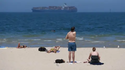 EPA Beachgoers apply sunscreen on a hot day in Melbourne