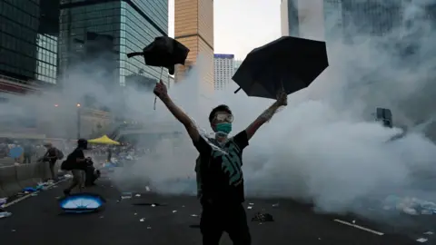 Reuters A protester (C) raises his umbrellas in front of tear gas which was fired by riot police to disperse protesters blocking the main street to the financial Central district outside the government headquarters in Hong Kong, September 28, 2014.