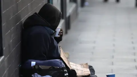 Getty Images homeless man sips drink