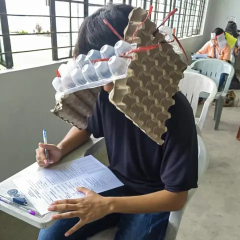 Mary Joy Mandane-Ortiz A student wears a homemade hat made of egg boxes during a college exam in the Philippines