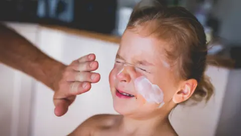 Getty Images sunscreen being applied to a child's face