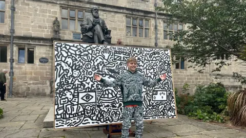 Doodle boy with a piece of art outside Darwin's school