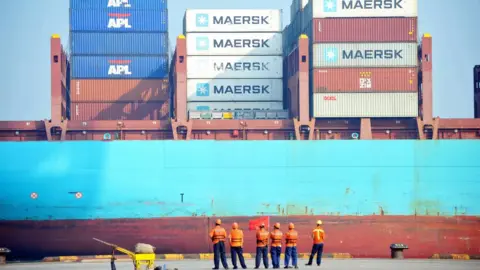 STR/AFP/Getty Chinese workers look as a cargo ship is loaded at a port in Qingdao, eastern China's Shandong province on July 13, 2017.