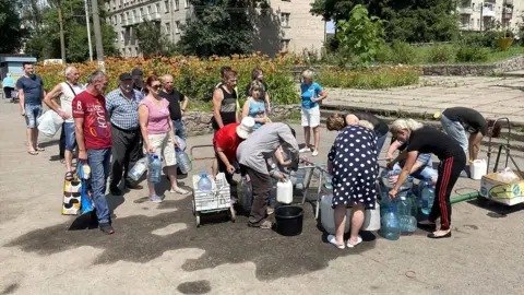 Ed Habershon/BBC People queue to access drinking water in the Ukrainian town Marhanets