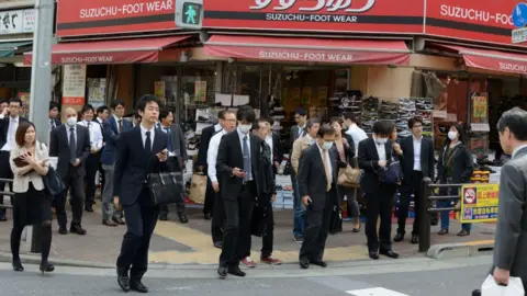 Getty Images Men and women in business attire cross a street on March 20, 2015 in Tokyo, Japan.