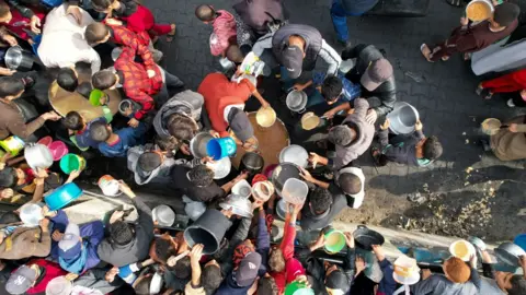 Reuters Palestinians gather to receive food cooked by a charity kitchen in Rafah in the southern Gaza Strip December 17, 2023