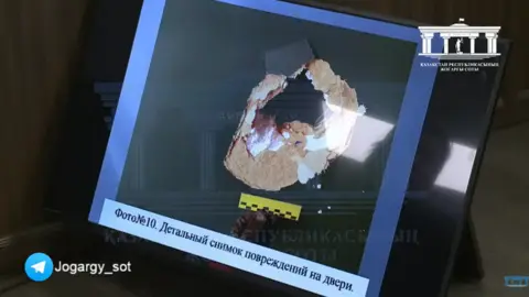 Supreme Court of Kazakhstan/YouTube Photo shown in court from the scene of the incident shows a hole in a toilet door