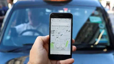 Reuters to a phone screen showing Uber app. A taxi can be seen in the background