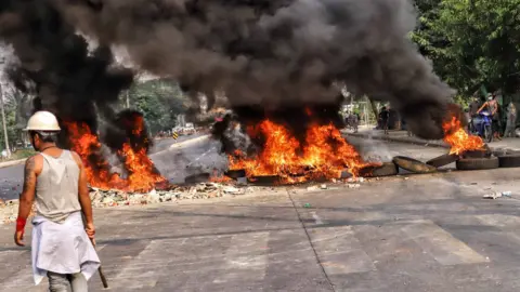 People clash with security forces as they continue to protest against the military coup and detention of elected government members in Hlaing Tharyar, Yangon