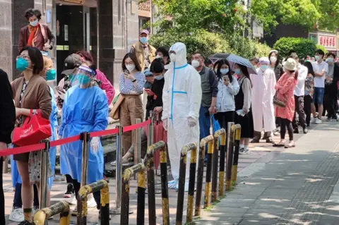 VCG via Getty Images Customers line up to enter a Carrefour supermarket on 3 May during Shanghai's phased Covid lockdown