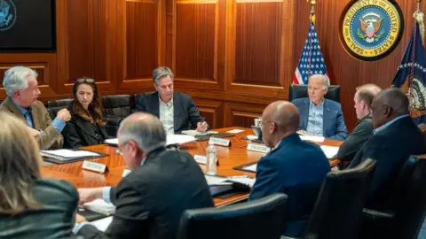 X/ @POTUS Joe Biden sits at a table and listens to members of the National Security Council