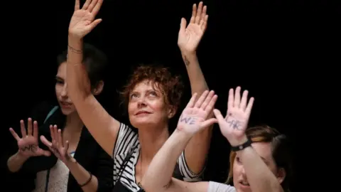 Reuters Susan Sarandon at demonstration, holding hands above her head