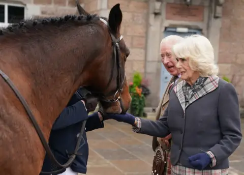 PA Media The King and Queen Consort and a horse