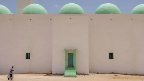 JOHN WESSELS/AFP A man arrives at the Grand Mosque for Friday prayers in Nouakchott on June 28, 2024. 