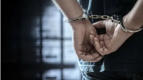 Getty Images Cuffed hands in police cell