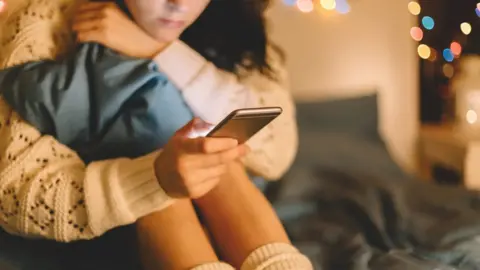 Getty Images A young girl looks at her phone in this staged photo