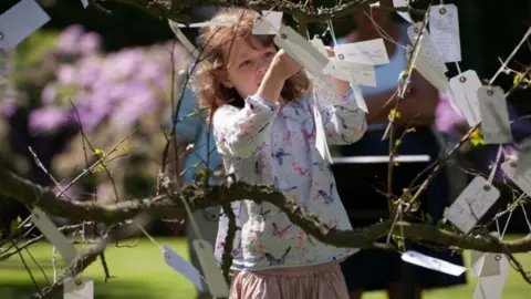 Yoko Ono Girl putting "wish" on "wish tree"