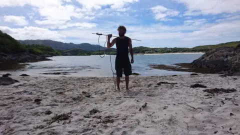 Chris Lewis Chris on a beach with a fishing spear