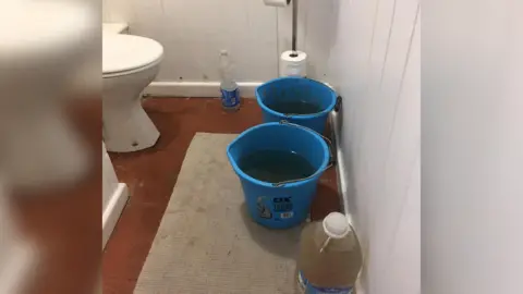 Rob Flanagan Buckets of water next to toilet