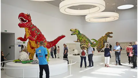 Lego Group People look at dinosaurs in the Masterpiece Gallery at Lego House