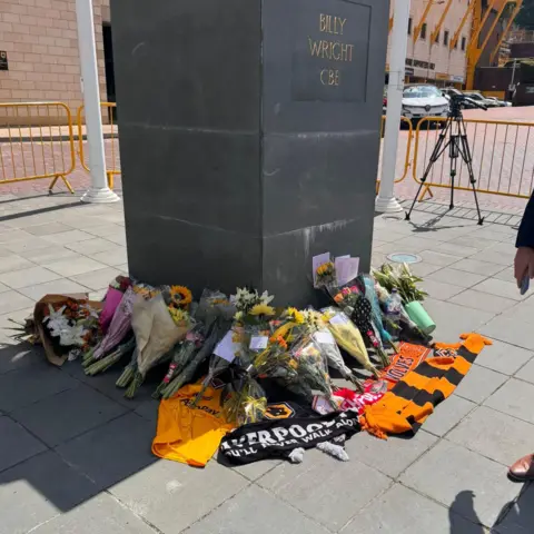 Manny Singh Bunches of flowers and several orange and black Wolves scarves are placed at the base of a statue outside Molineux Stadium in Wolverhampton.