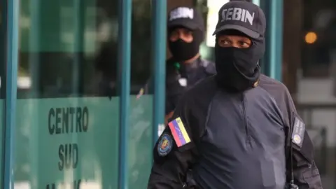 EPA Members of the Sebin intelligence service stand outside the building housing the office of Venezuela's opposition leader Juan Guaidó in Caracas, 21 January 2019