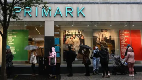 AFP via Getty Images Shoppers queue outside Liverpool's Primark store