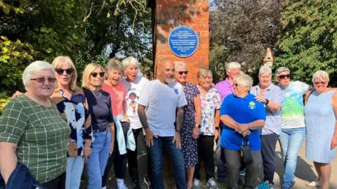 Louise Parry/BBC Players and coaches family with blue plaque