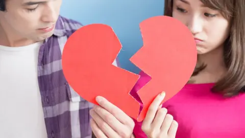 Getty Images Couple pose with broke heart sign