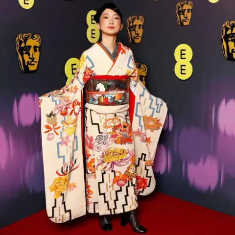 Getty Images Shiori dalam kimono putih dengan detail oranye, kuning dan hitam