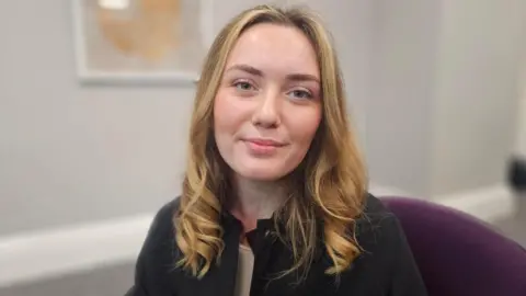 Phoebe Lake, sitting in a chair as part of the presentation