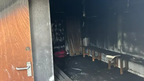 BBC Changing rooms badly damaged by fire, with soot and scorch marks on the walls and floors