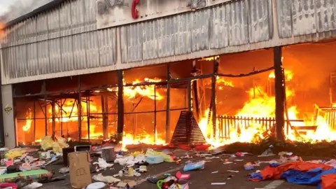 Reuters A fire engulfs Campsdrift Park, which houses Makro and China Mall, following protests that have widened into looting in Pietermaritzburg, South Africa, 13 July 2021