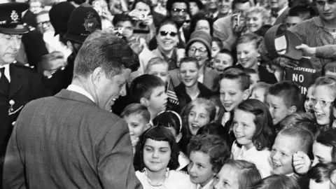 Getty Images President Kennedy greets British children as he arrives at the American Embassy in London, in 1961