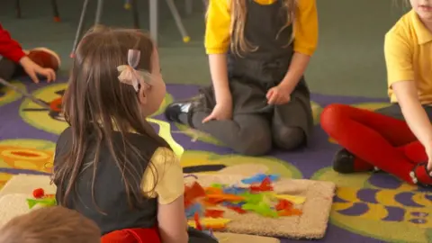 BBC Schoolchildren sitting on a carpet