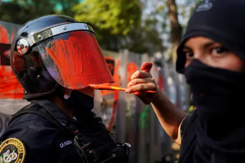 Toya Sarno Jordan / Reuters A demonstrator paints the helmet visor of a riot police officer, in Mexico City, Mexico, 11 November 2020