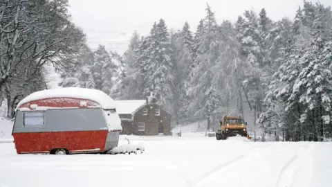 Owen Humphreys/PA A snow plough passes an old caravan in Nenthead, Cumbria