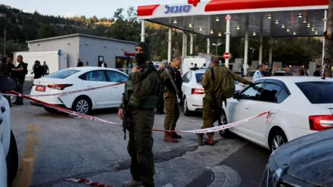 Reuters Israeli security personnel at a petrol station near the West Bank settlement of Eli where four Israelis were shot dead by two Palestinian gunmen (20 June 2023)