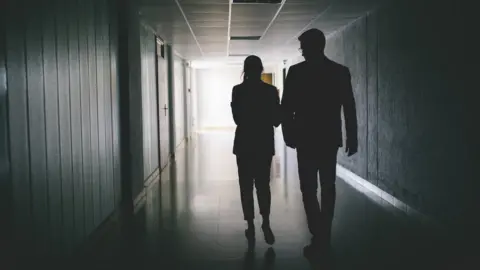 Getty Images Silhouette of a man and a woman at work