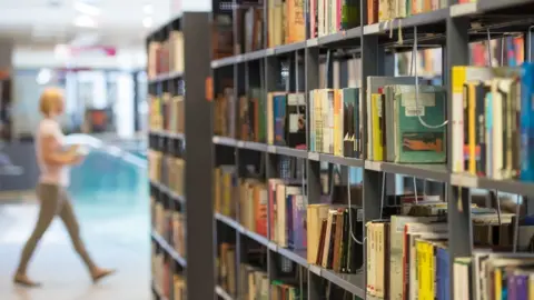 Getty Images woman in library by shelf of books